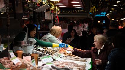 Una comerciante cobra a una señora, en el Mercado de la Boquería, en Barcelona.