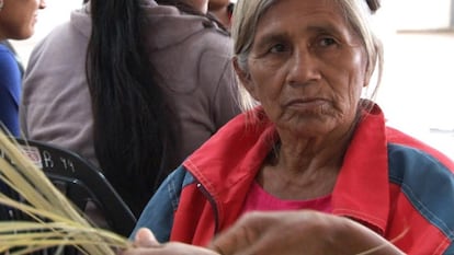 Mujer qom realizando un canasto con hojas de palma