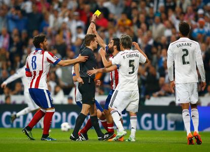 La tensión de la eliminatoria de Champions entre los dos equipos de Madrid se dejó notar en los dos partidos. Arda Turan reacciona a una tarjeta amarilla agarrando la mano del árbitro.