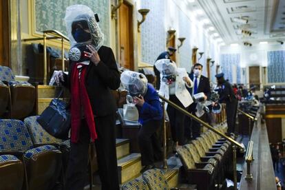 Asistentes a la sesión se refugian en la galería de la Cámara mientras los manifestantes intentan invadir la sala principal del Capitolio.