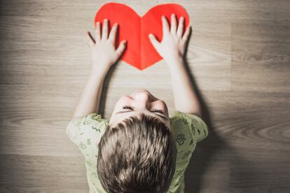 Un niño sujeta un corazón de papel.