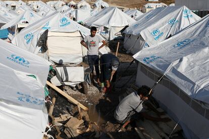 Tres hombres reparan sus tiendas en uno de los campamento para refugiados en la isla griega de Lesbos, el pasado mes de octubre.