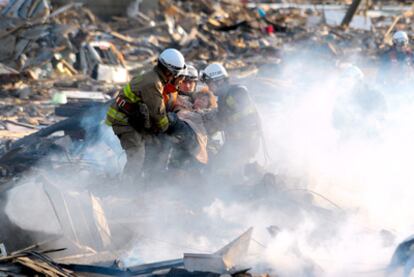 Los bomberos rescatan a una superviviente del tsunami, ayer en la devastada ciudad de Natori, al sur de Sendai, la zona más castigada por la tragedia.