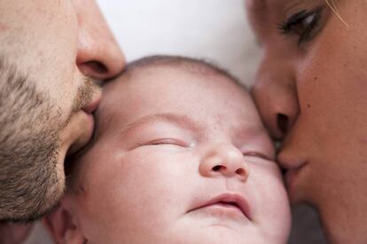 Bebé durmiendo con los padres al lado.