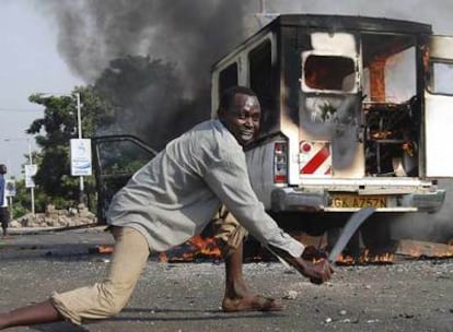 Un opositor empuña un machete en medio de la carretera cerca de una furgoneta incendiada ayer cerca de Kisumu.
