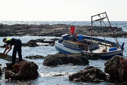 Dos agentes de la policía inspeccionan la barca encallada en Binisafúa (San Luis en la costa sur de Menorca).