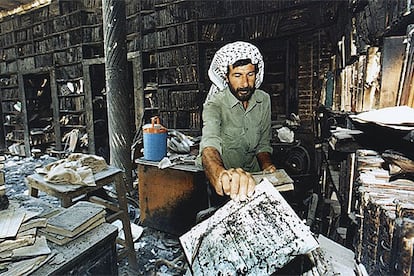 Un iraquí recoge los restos de los libros quemados en una biblioteca de Bagdad en agosto de 1999.