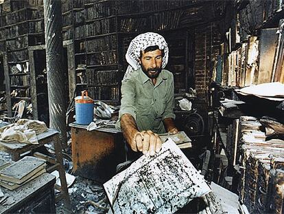 Un iraquí recoge los restos de los libros quemados en una biblioteca de Bagdad en agosto de 1999.