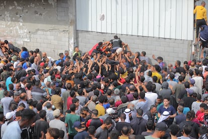 Una multitud de palestinos desplazados se amontona en la ventana de una panadería en el campo de refugiados de Nuseirat para conseguir pan, este jueves.