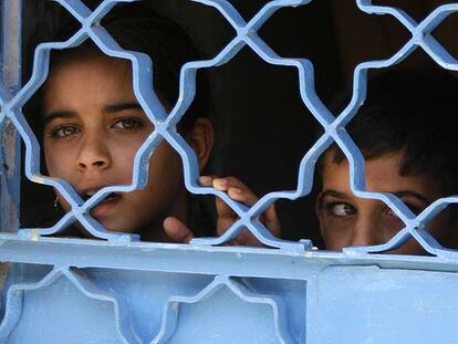 Dos niños observan una patrulla de soldados estadounidenses en Bagdad desde la puerta de su casa.