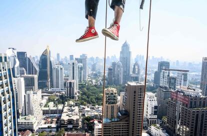 Las piernas de un trabajador que escala un rascacielos para instalar luces de Navidad en Bangkok (Tailandia).