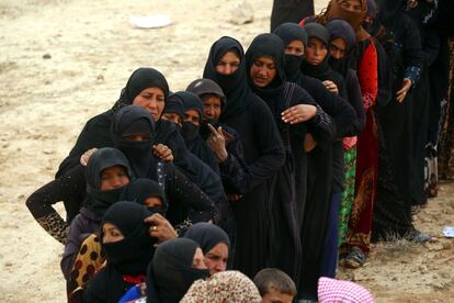 Displaced Syrian women, who fled the countryside surrounding the Islamic State (IS) group stronghold of Raqa, stand in a queue at a temporary camp in the village of Ain Issa on April 28, 2017. / AFP PHOTO / DELIL SOULEIMAN