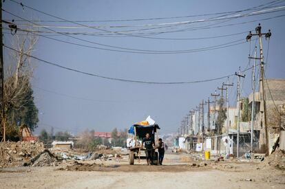 Dos iraquíes tiran de un carro con sus pertenencias, en el barrio de Al-Intisar en el sureste de Mosul (Irak).