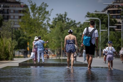 Varias personas se remojan los pies en una fuente ornamental del parque de les Glòries durante una ola de calor. 