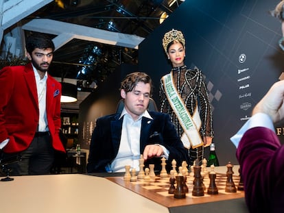 Carlsen (sentado), Gukesh (de pie) y Aronián analizan este viernes una posición inicial junto a Miss Angola, invitada especial para la inauguración del torneo