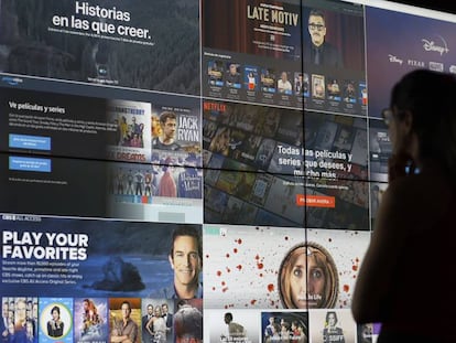 Una joven contempla una pantalla gigante con distintas plataformas de televisión online.