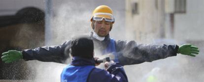 Un operario quita con agua el polvo de un voluntario en las tareas de reconstrucción de las zonas devastadas por el tsunami.