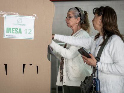 Una mujer asiste a otra para votar, el 29 de octubre en la Secretaría Distrital de Bogotá (Colombia).
