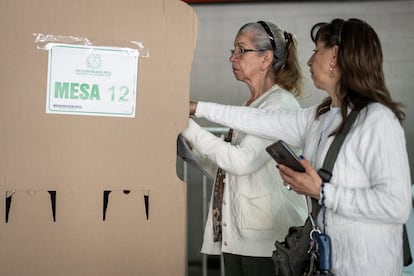 Una mujer asiste a otra para votar, el 29 de octubre en la Secretaría Distrital de Bogotá (Colombia).
