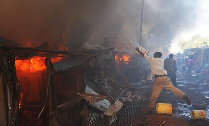 Hombres kenianos utilizan baldes de agua para apagar un incendio, provocado por un fallo eléctrico de una de las residencias, que arrasa casas en los tugurios Deep Sea en Nairobi.