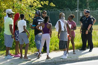 Residents talk with Jacksonville police officers near the scene of a mass shooting at a Dollar General store, Saturday, Aug. 26, 2023, in Jacksonville, Fla.