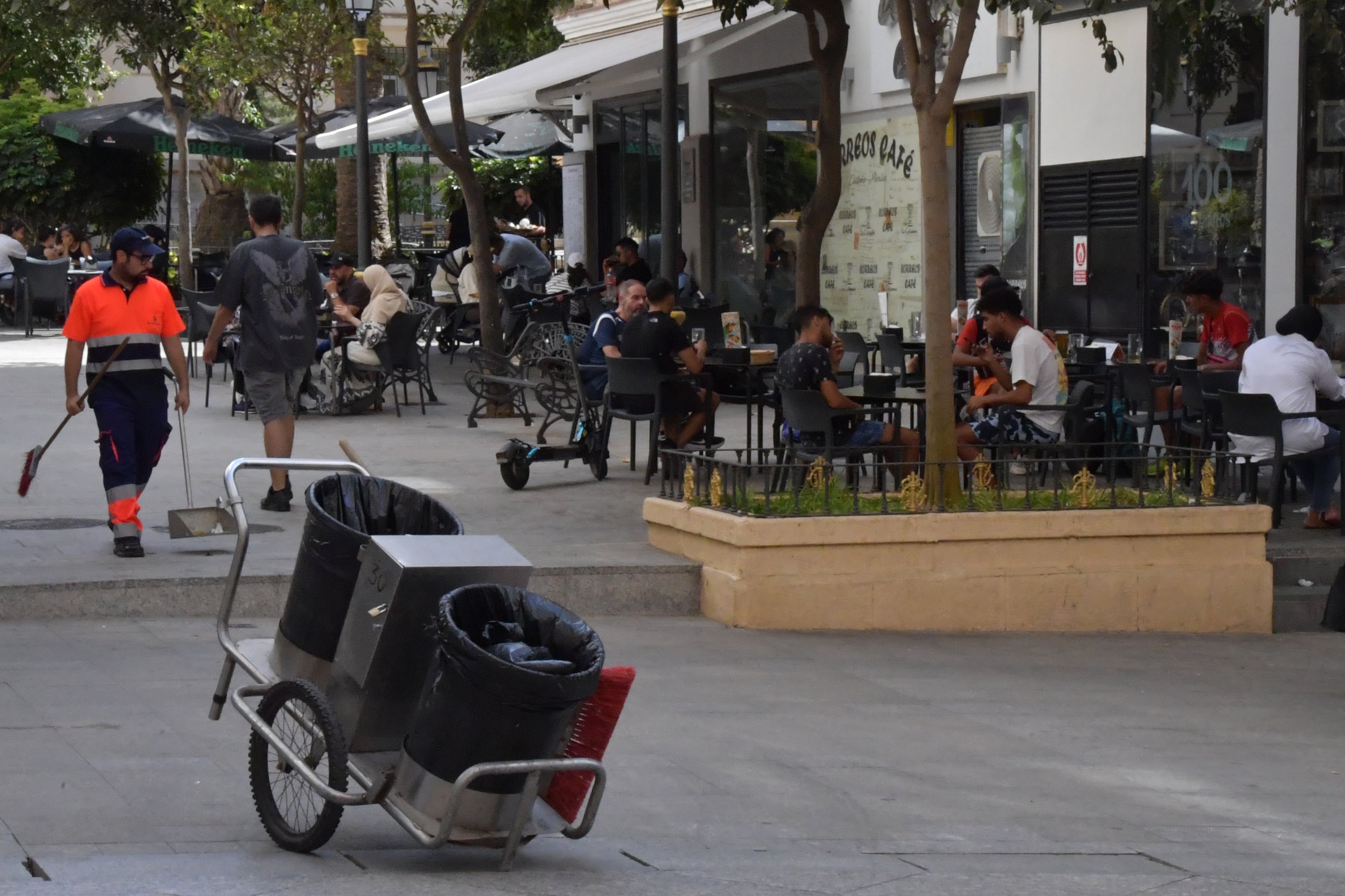 Un barrendero y clientes en terrazas, el jueves en Ceuta.