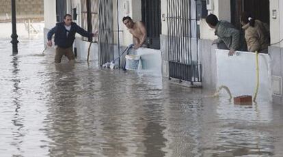 Vecinos de la barriada Virgen de Setefilla de Lora del Río (Sevilla) tratan de achicar el agua que ha inundado sus viviendas.