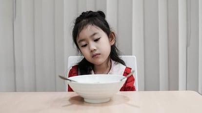 Una niña mira la comida sin hambre. 
