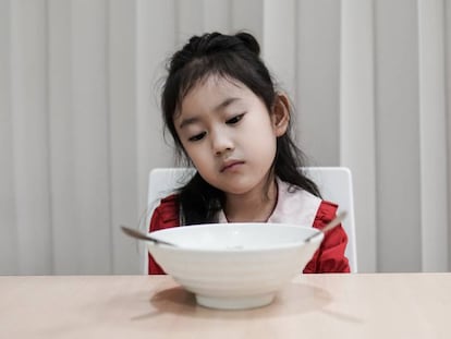 Una niña mira la comida sin hambre. 