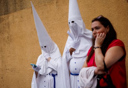 Penitentes pertenecientes a la hermandad de La Paz esperan antes de participar en una procesión del Domingo de Ramos en Sevilla, el 24 de marzo.