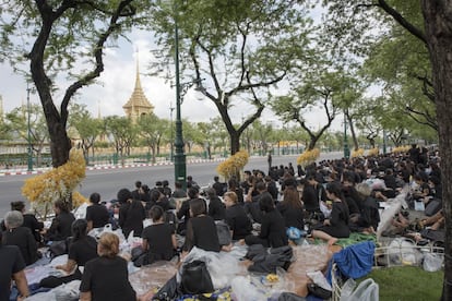 Miles de tailandeses, procedentes de varias provincias, han ido ocupando sitios cerca de la plaza Sanam Luang, en Bangokok, donde tendrá lugar el funeral del monarca este viernes. En la imagen, un grupo de personas espera este miércoles cerca del Palacio Real.
