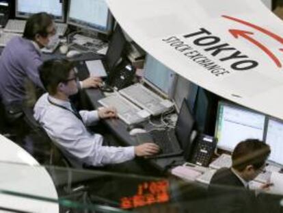 Corredores de bolsa permanecen atentos a la información bursátil en Tokio.