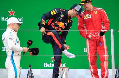 Después del fiasco de la anterior carrera en Baréin donde ninguno de los dos pilotos de Red Bull logró acabar (Ricciardo se paró al quedarse sin energía en la primera vuelta y Verstappen reventó un neumático y también quedó fuera), los mecánicos del equipo se resarcieron gracias a su apuesta de poner neumáticos de compuesto blando para las últimas vueltas. En la imagen, Daniel Ricciardo (centro) se quita la bota en el podio.