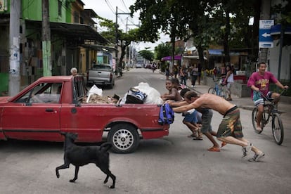 Un grupo de vecinos ayuda a empujar un coche en el barrio.