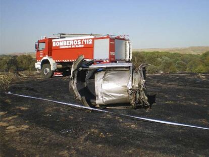 Delante del camión de bomberos, los restos de la turbina derecha del MD-82 con uno de los  sistemas de freno del avión, la reversa (la parte metálica que sobresale a la izquierda del motor), desplegada.