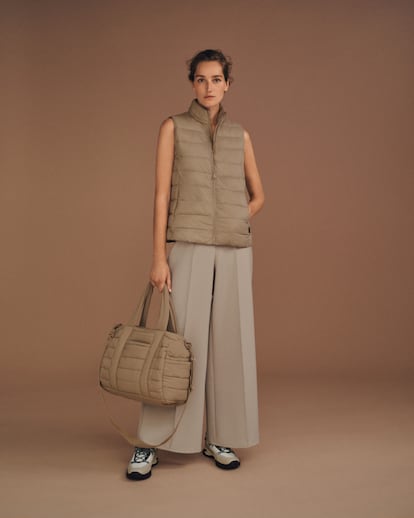 La modelo posa con chaleco Primaloft® Waterblock, pantalón ancho con tejido de alta resistencia, deportivas Vibram® montaña y bolsa gym acolchada. Todo, de OYSHO.