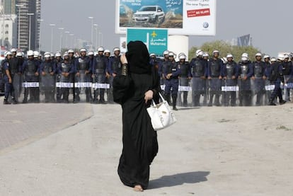 Una manifestante vistiendo un abaya camina frente a miembros de la policía antidisturbios en Manama, la capital de Bahréin, durante las protestas registradas el 13 de enero.