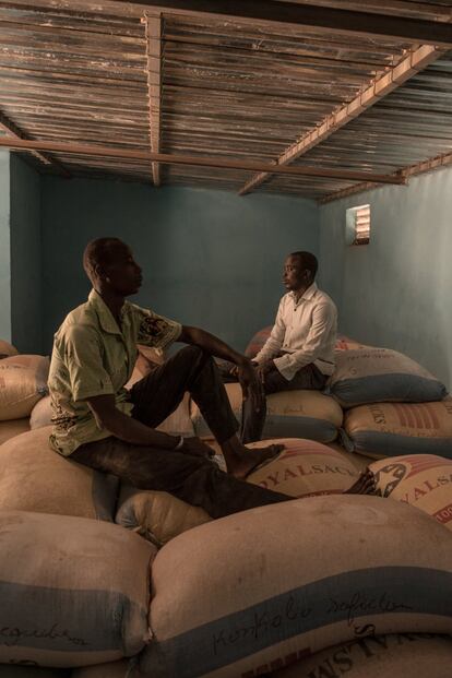 Dos trabajadores en un almacén construido gracias a la ayuda de la ONG italiana Mani Tese. Los productores disponen de una herramienta de microfinanzas llamada 'warratage' que permite a los miembros de organizaciones campesinas obtener un préstamo comprometiendo sus cultivos como garantía, cuyo precio tiende a aumentar. La cosecha se coloca en un almacén como el de la imagen con dos candados, uno es de la organización campesina y otro está en posesión del banco que otorga el préstamo. A cambio, el agricultor tiene derecho a un préstamo de aproximadamente el 75 u 80% del valor de la cosecha que ha almacenado.