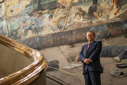 Arturo Zaldívar Lelo de Larrea, posa para una fotografía en el mural 'Siete crímenes mayores' del artista Rafael Cauduro