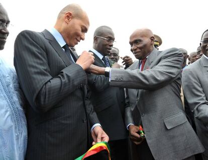 Abdoulaye Wade ajusta una medalla en la chaqueta de su hijo, Karim, durante un acto celebrado en Dakar en 2011.