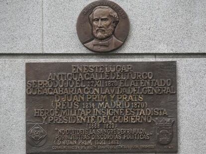 Placa dedicada a Juan Prim y Prats en el cruce de Alcalá con Marqués de Cubas, sobre el muro exterior del Banco de España.