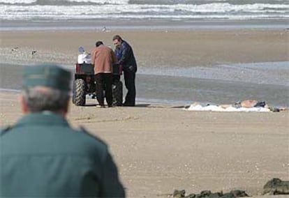 Un guardia civil observa el levantamiento de cadáveres en la playa de Rota.