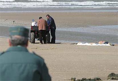 Un guardia civil observa el levantamiento de cadáveres en la playa de Rota.