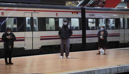 Usuarios esperan la llegada de un tren de Cercanías en la estación de Atocha, en Madrid.