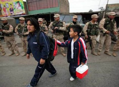 Una mujer y su hijo pasan ante un control militar en las afueras de Lima.