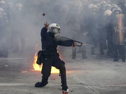 Un policía lanza un objeto a los manifestantes en las protestas de hoy en Atenas