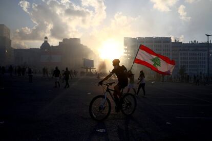 Un manifestante sujeta una bandera de Líbano mientras cruza en bicicleta una calle céntrica de Beirut.