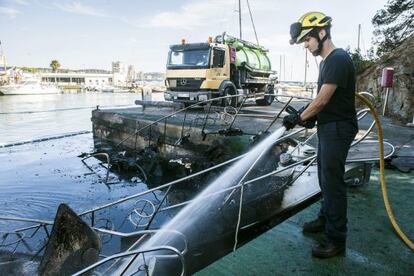 Un bombero extingue las llamas de uno de los barcos.