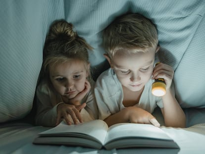 Dos niños leen en la cama.