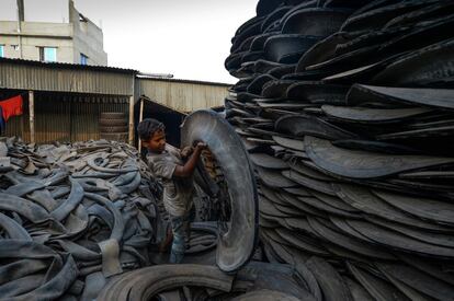 Un niño trabaja con piezas de una llanta vieja en Dhaka (Bangladesh).